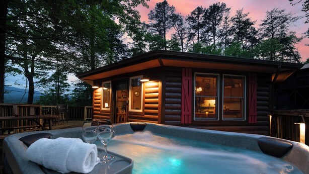 Eine Blockhütte mit Whirlpool und Holzterrasse.