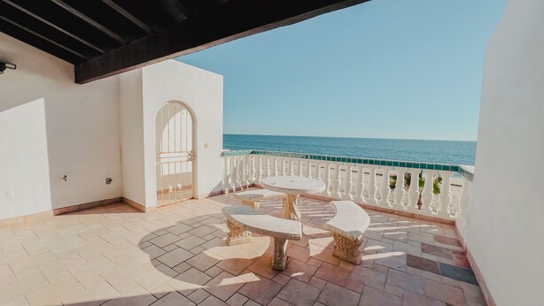 Ein Balkon mit Meerblick, eine weiße Tür und ein kleiner Tisch mit zwei Stühlen.