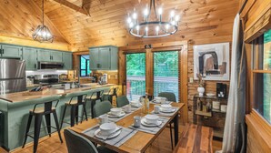 A wooden cabin interior with a dining area, kitchen, and bar. - Newly Renovated! NEW deck & SAUNA! 3 King Bedrooms! Hot tub/Arcade. Free tickets (Sevierville)