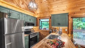 A modern kitchen with wooden cabinets, stainless steel appliances, and a wooden countertop with a snack drawer. - Newly Renovated! NEW deck & SAUNA! 3 King Bedrooms! Hot tub/Arcade. Free tickets (Sevierville)