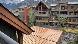 A multi-story hotel with a wooden facade, large windows, and a view of snow-capped mountains. - Luxury King Suite- Mountain Views/ 2 Balconies/Pool/Hot tub (Canmore)