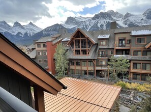 A multi-story hotel with a wooden facade, large windows, and a view of snow-capped mountains. - Luxury King Suite- Mountain Views/ 2 Balconies/Pool/Hot tub (Canmore)