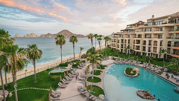A resort with a pool, palm trees, and a view of the ocean.