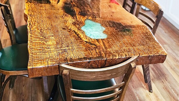 A rustic wooden dining table with a woven table runner, surrounded by wooden chairs with green cushions. - Quaint Cabin - 8 minutes from Ark Encounter!!
Country setting, near town!! (Dry Ridge)