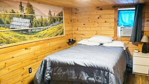 A wooden cabin bedroom with a bed, a nightstand, a lamp, a window with curtains, and a painting on the wall. - Quaint Cabin - 8 minutes from Ark Encounter!!
Country setting, near town!! (Dry Ridge)
