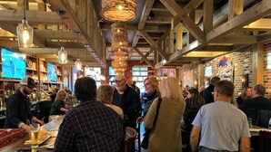 Un bar affollato con travi in legno e luci a sospensione.