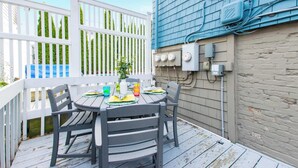 Een terras met een tafel voor twee personen, omringd door wit schuttingwerk, en functionele kasten tegen de aangrenzende muur.