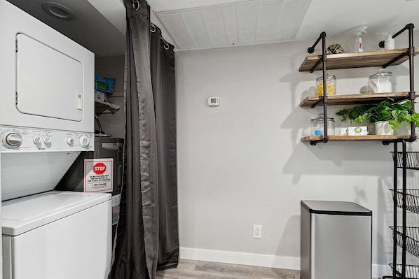 A laundry area with a washing machine, dryer, and a metal rack with shelves. - Sapphire at McCormick Ranch * Modern 2BR, 2BA Condo w/ Heated Pool, Spa & Tennis Court! (Scottsdale)