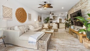 A modern living room with a sofa, coffee table, and a TV on a stone wall. - 3 Bedroom Oasis with Private Pool (Casuarina)