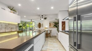 A modern kitchen with a large island, stainless steel appliances, and a ceiling fan. - 3 Bedroom Oasis with Private Pool (Casuarina)