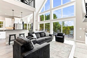 A spacious living area with a large window, a modern kitchen, and a balcony with outdoor furniture.