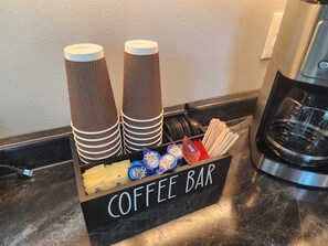 Een koffiebar met stapels wegwerpbekers, een koffieapparaat en diverse koffiepads.