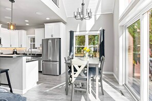 A modern kitchen with a central island, stainless steel appliances, and a dining area with a view to the outdoors.