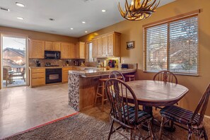 A spacious kitchen with wooden cabinets, a granite countertop, and a dining area with a wooden table and chairs.