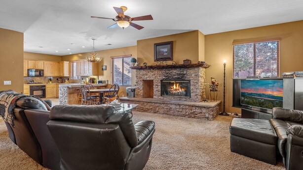 A spacious living room with a fireplace, leather sofas, a television, and a kitchen in the background. - Bear Snugglin - Close to Slopes, Hot Tub, Deck, Barbecue (Big Bear Lake)