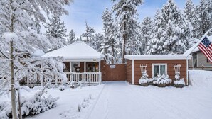 Een pand bedekt met sneeuw, met een houten chalet, een veranda en een garage.