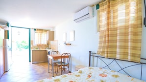 Un dormitorio con cama, escritorio, silla y kitchenette.