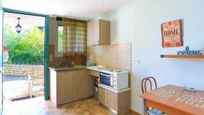 Una cocina compacta con horno integrado, una mesa de comedor con sillas y vistas al exterior.