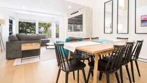 Ein modernes Wohnzimmer mit einer Couch, einem Couchtisch und einem Essbereich mit einem Holztisch und Stühlen.