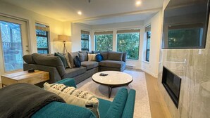 Ein modernes Wohnzimmer mit einer Eckcouch, einem runden Couchtisch und einem Kamin.