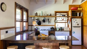 Una cocina con una isla central, taburetes de madera, una estufa y diversos utensilios de cocina.