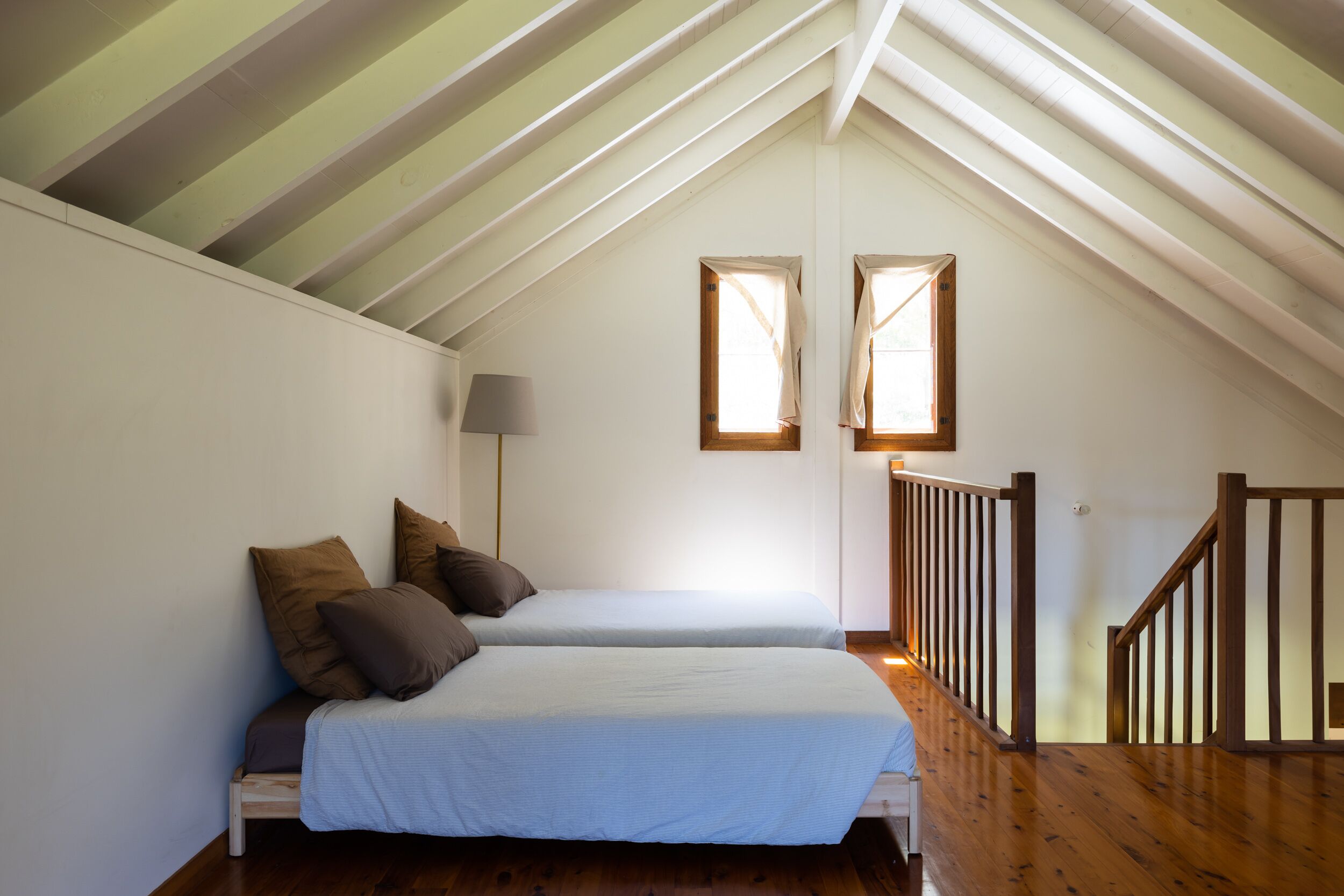 A bedroom with two beds, a wooden staircase, and a skylight.