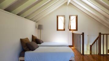 A bedroom with two beds, a wooden staircase, and a skylight.