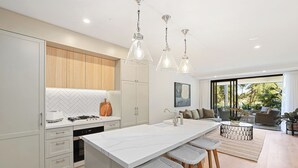 Una cocina moderna con una isla central, taburetes de bar e iluminación colgante.