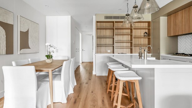Una cocina moderna con armarios blancos, encimeras de madera y taburetes de bar.