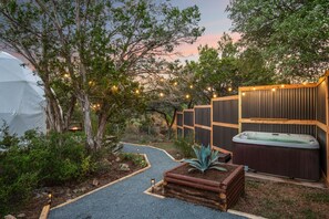 A spa area with a hot tub, wooden deck, and string lights. - Hill Country Glamping Dome w/Hot Tub, Gym, Sauna & Cold Plunge (Spicewood)