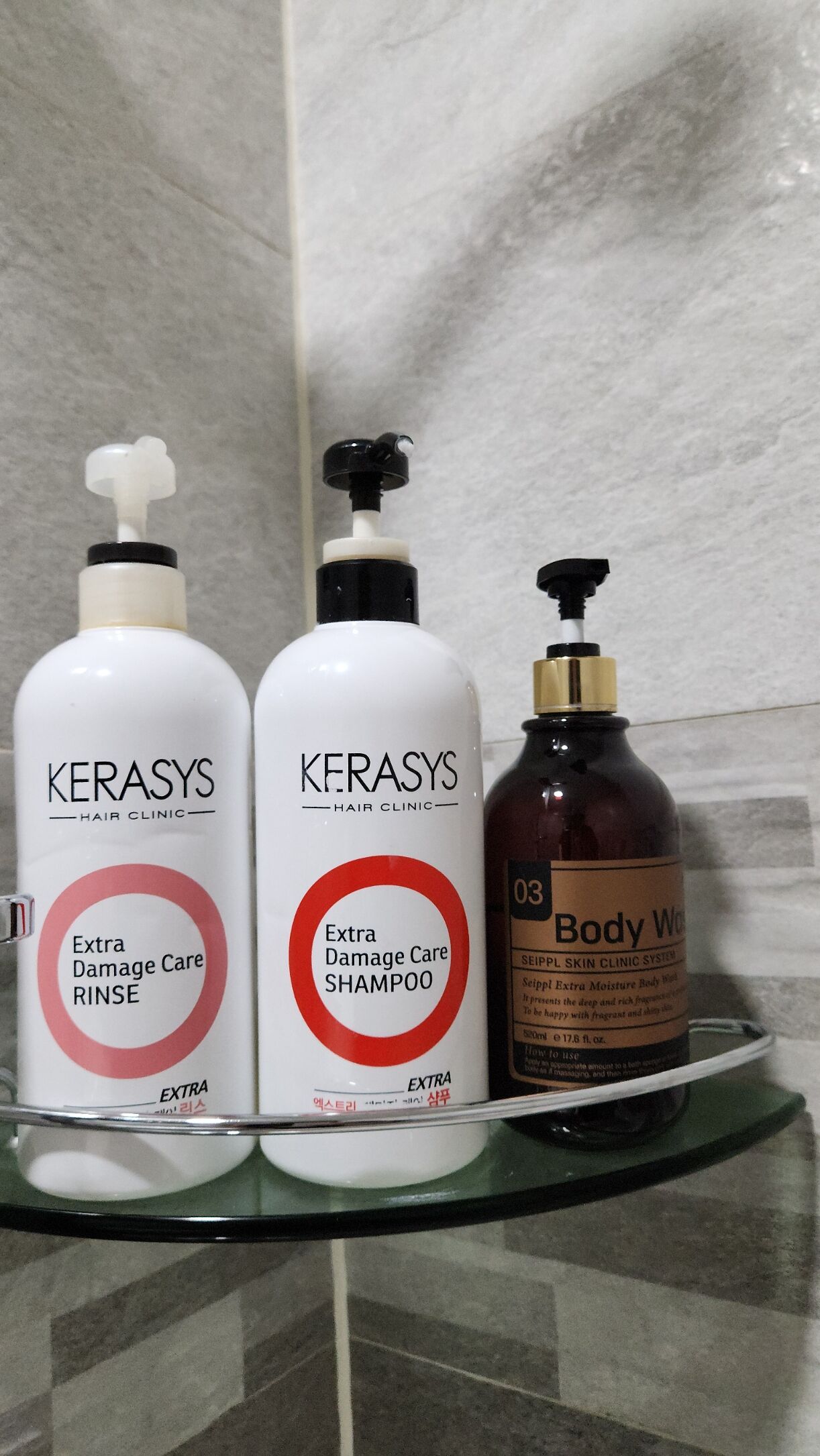 Three bottles of Kerasys hair clinic products on a glass shelf.