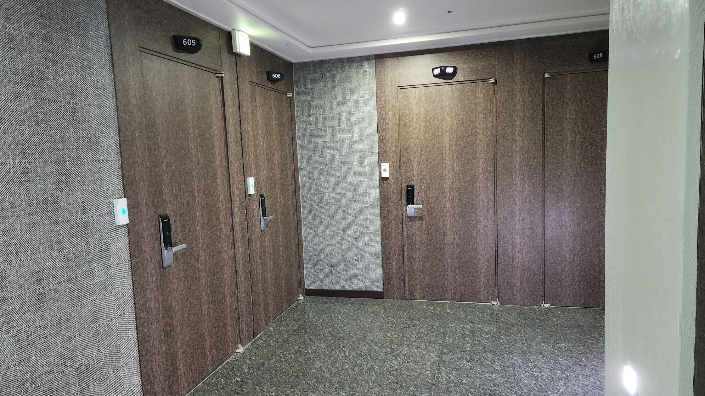 Un pasillo con cuatro puertas de madera, cada una con un número.