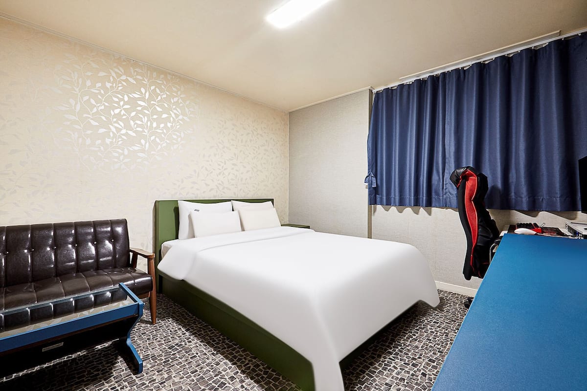 A hotel room with a bed, a sofa, a desk, and a chair.