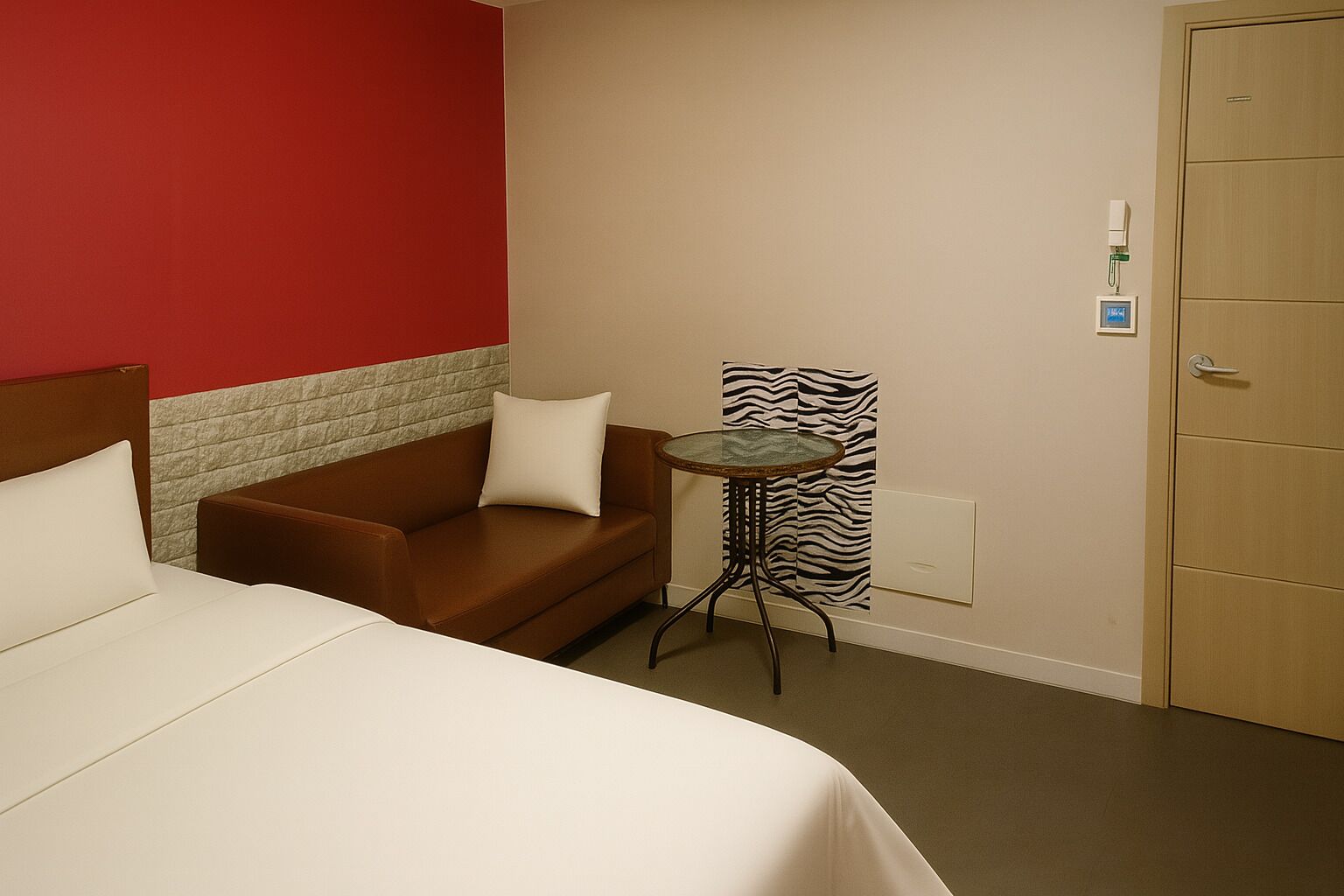 A hotel room with a bed, a brown sofa, a small round table, and a zebra-patterned curtain.