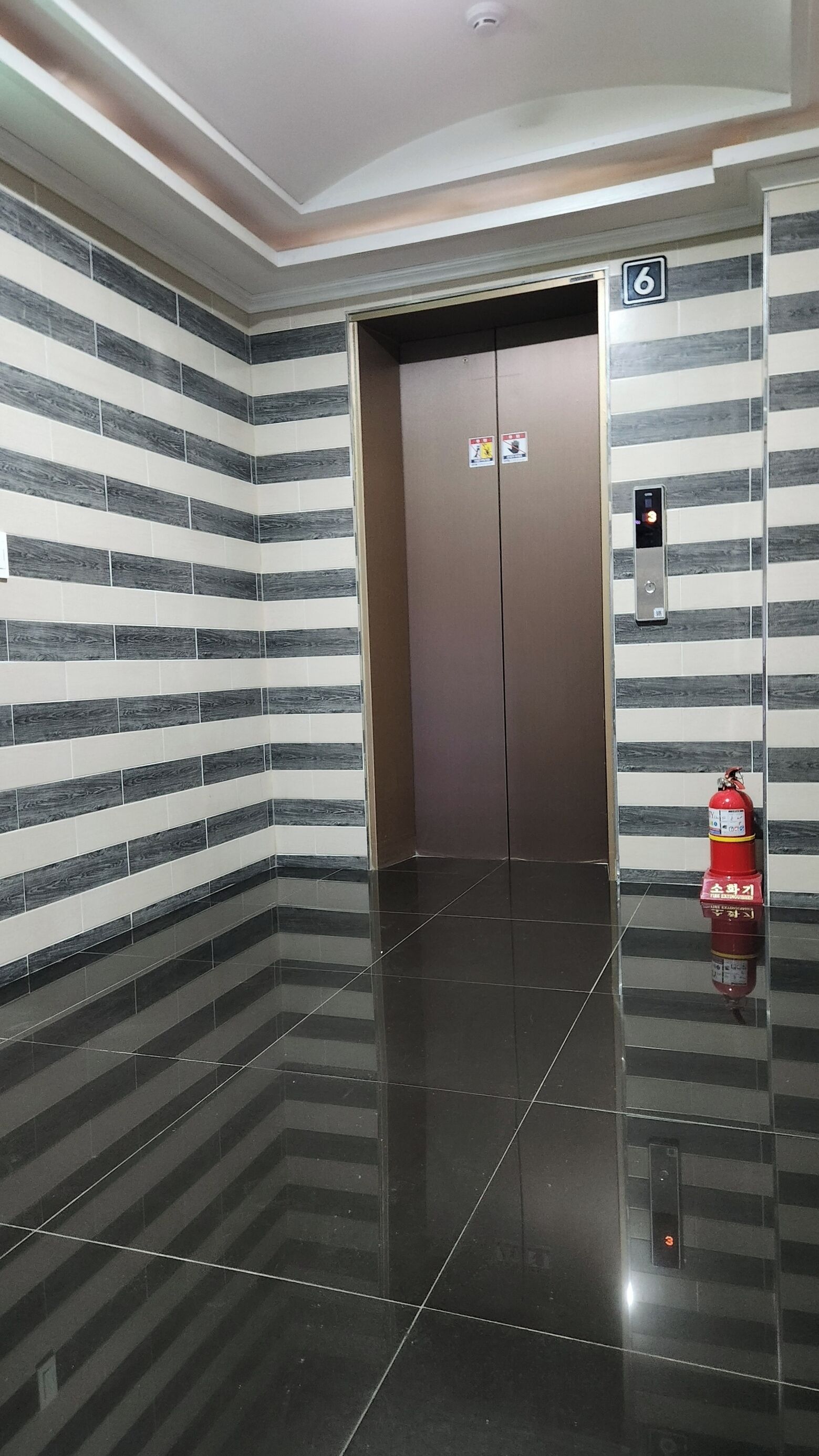 An elevator with a digital display and emergency equipment.