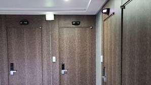 Un couloir avec trois portes en bois, chacune portant un numéro.
