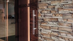 L’entrée d’un hôtel, avec une porte en verre, un mur en pierre et une enseigne au-dessus de la porte.