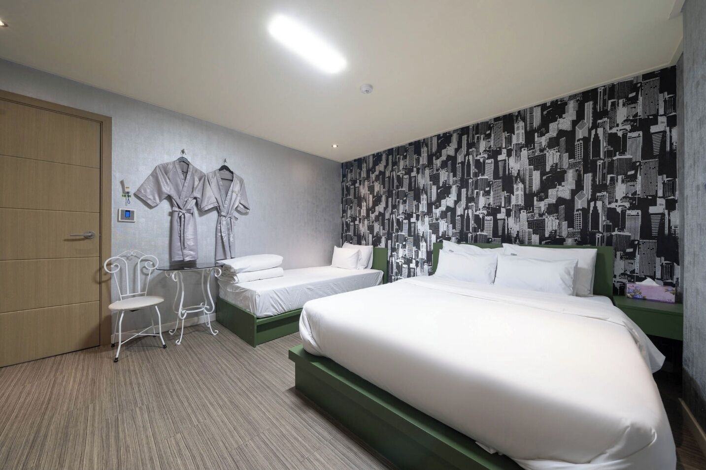 Quarto de hotel com duas camas, área de estar com cadeiras e um guarda-roupa.