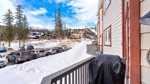 A snowy residential street with parked cars and houses.