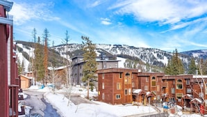 A wooden building with multiple windows and a ski slope in the background. - The Powderhound Condo (Whitefish)