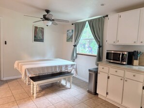 A kitchen with a microwave, cabinets, a bench, and a ceiling fan. - Bigfoot Bungalow (Crescent City)