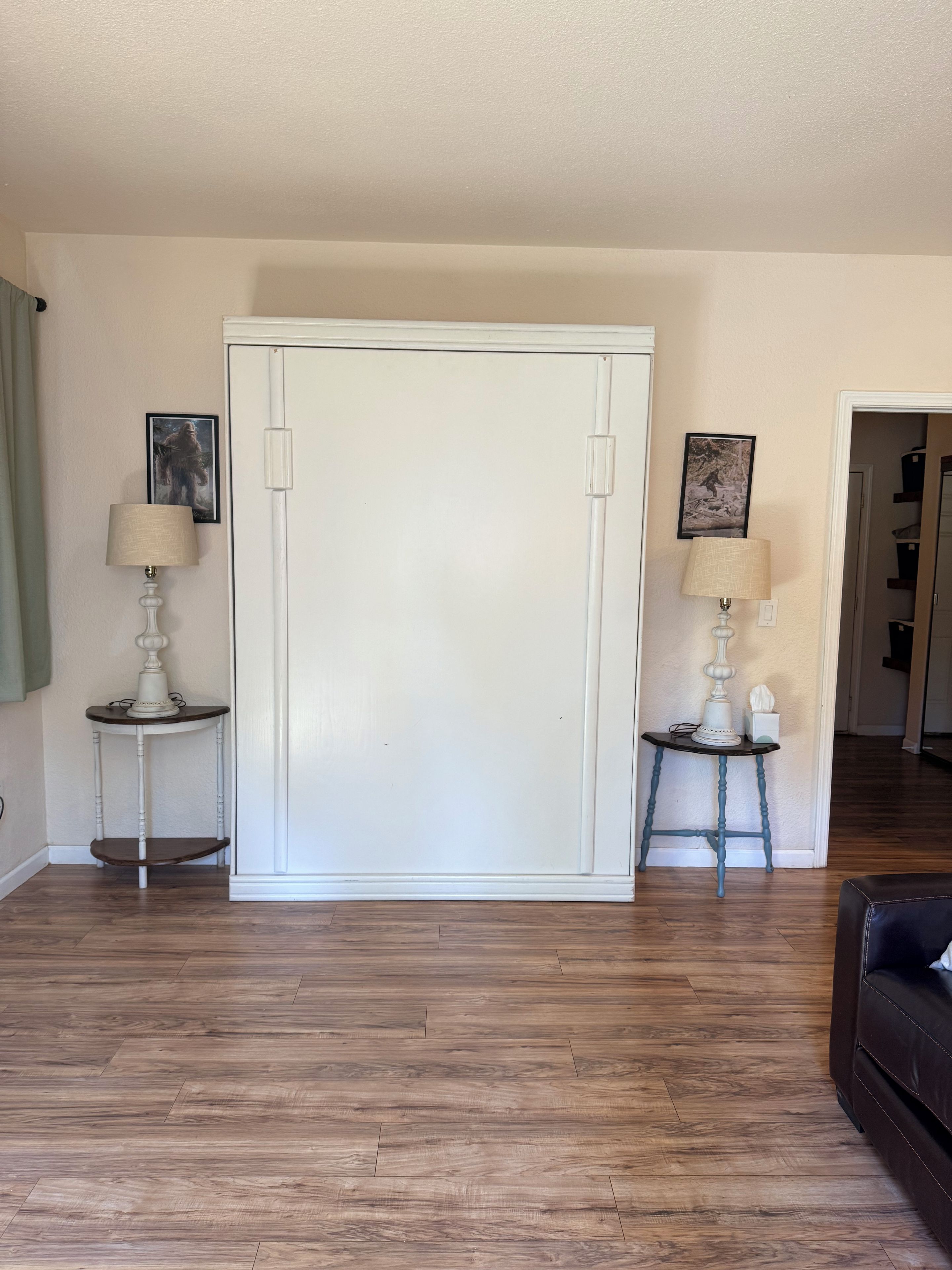 Una habitación con un armario blanco, dos mesitas de noche con lámparas, y suelo de madera.