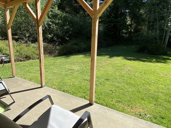 Un patio techado con piso de concreto y pilares de madera.