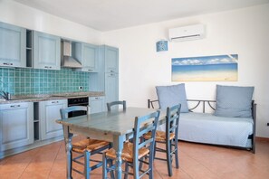 A compact kitchen with blue cabinets, a dining table with chairs, and a sofa.
