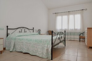 Un dormitorio con cama, mesita de noche, cómoda y ventana con cortinas.