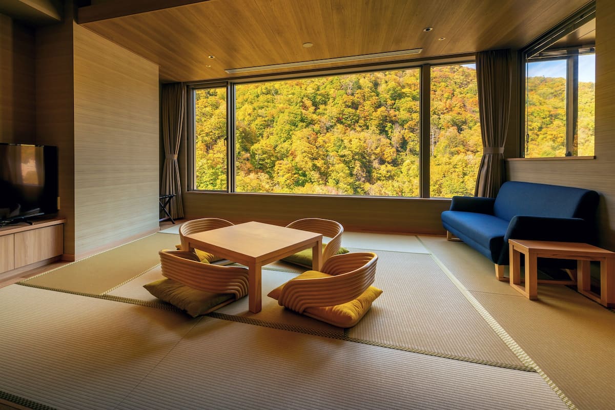 A modern living room with tatami flooring, a wooden table, and a sofa.