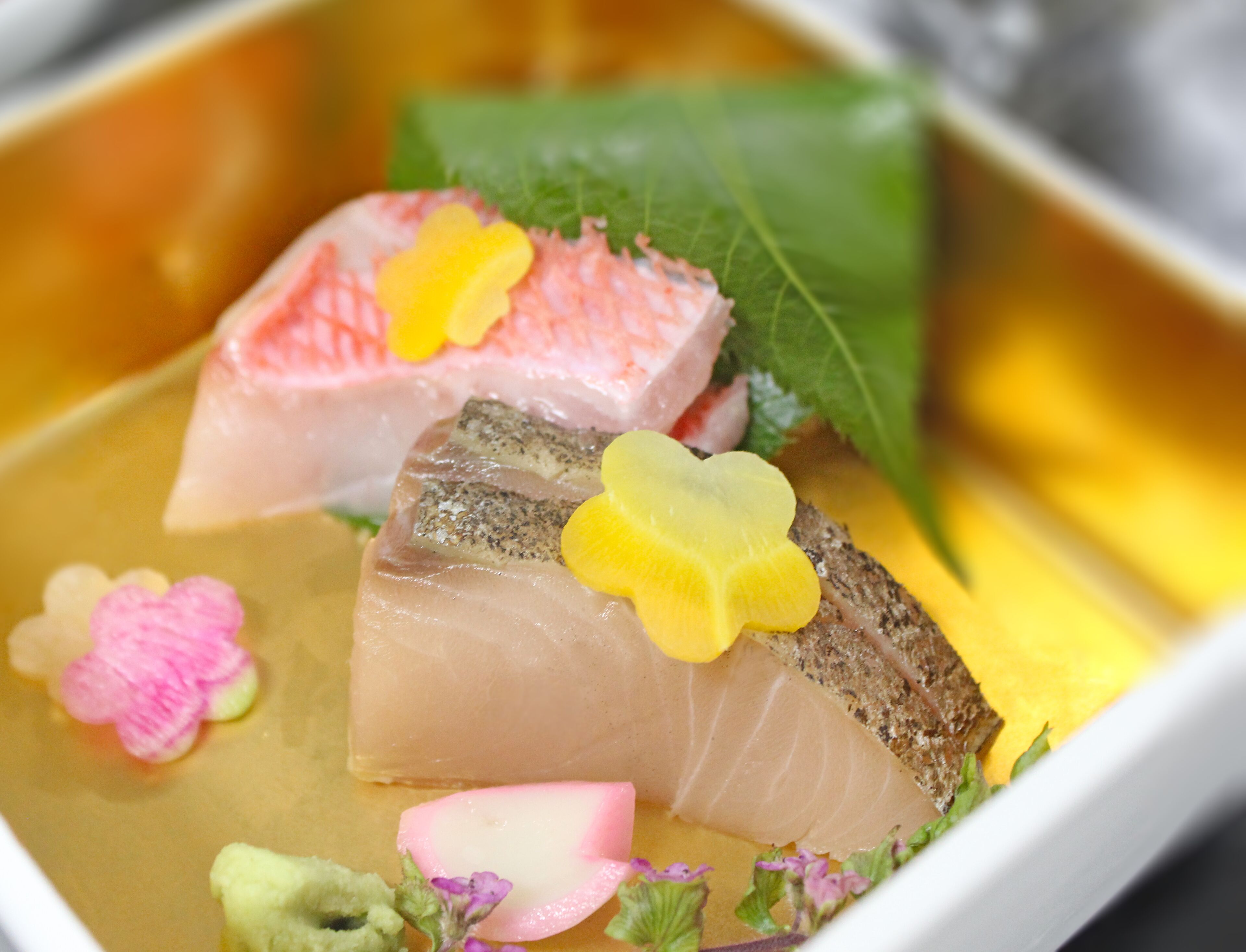 A dish with various food items including fish, vegetables, and decorative elements.
