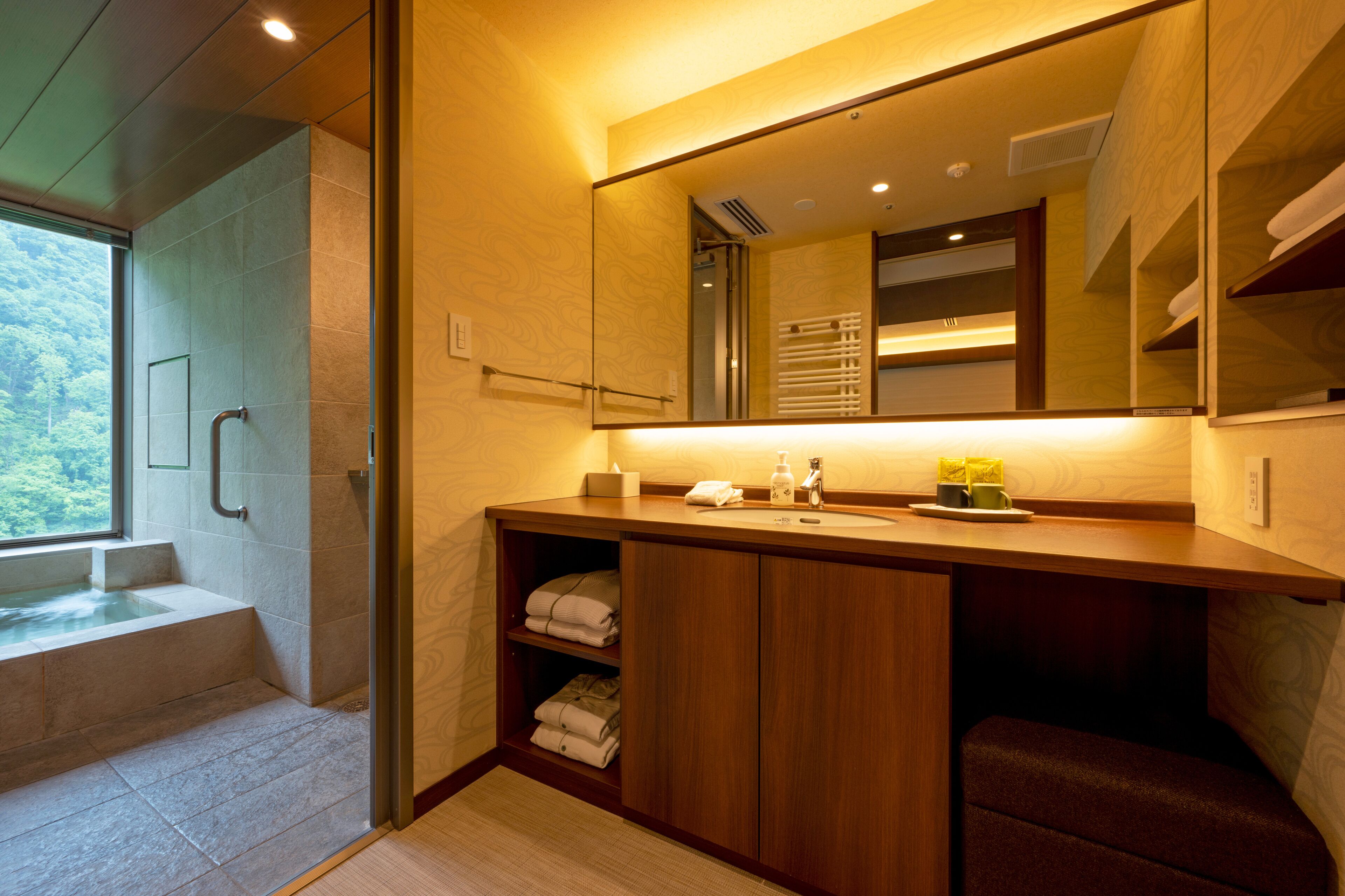 A modern bathroom with a glass shower enclosure, wooden vanity, and a large mirror.