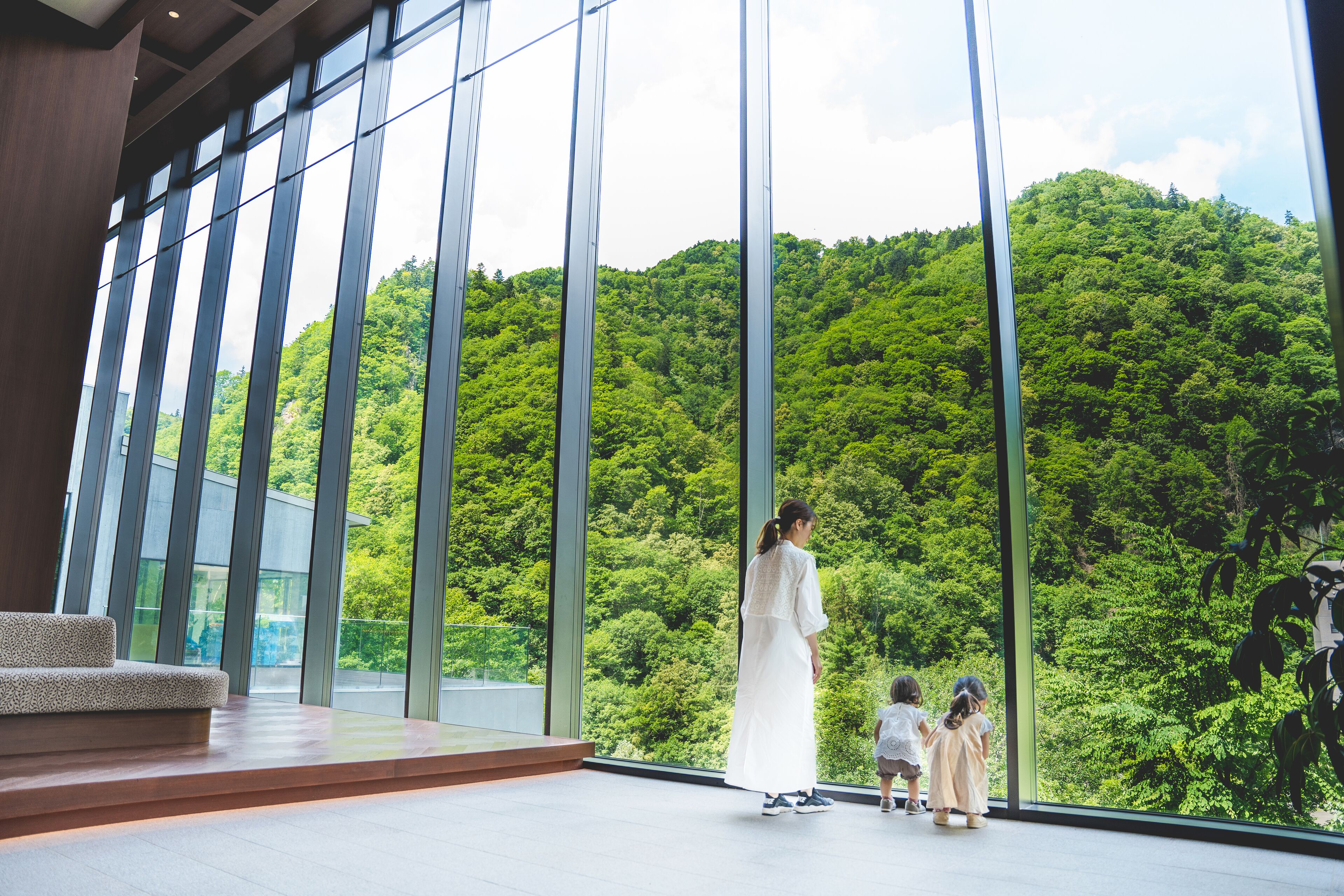 A spacious room with large windows offering a view of a lush forest.