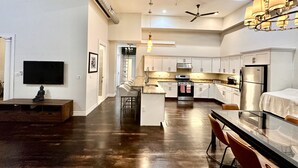 A spacious kitchen with a central island, stainless steel appliances, and a ceiling fan.